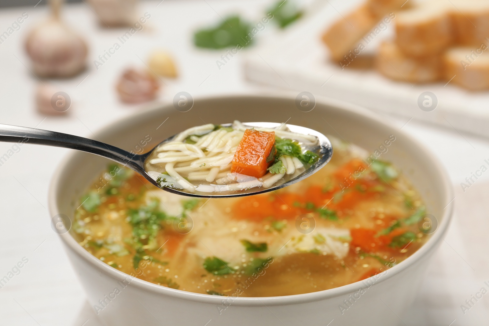 Photo of Spoon with fresh homemade chicken soup on blurred background, closeup