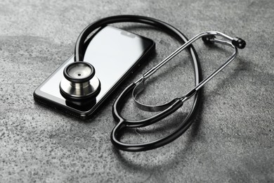 Photo of Modern smartphone and stethoscope on grey table