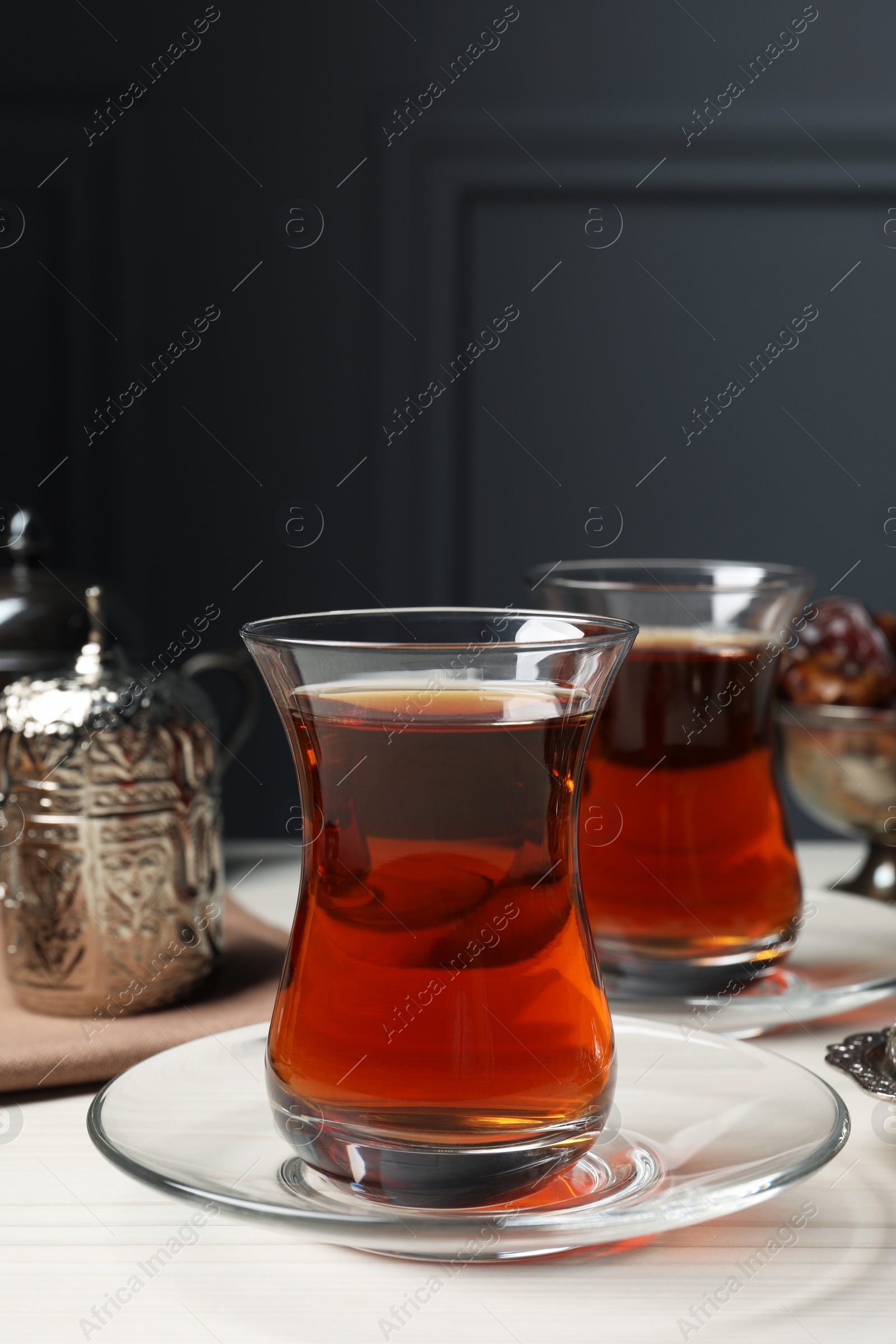 Photo of Glasses of tea and vintage tea set on white wooden table