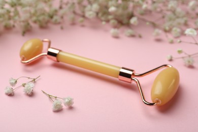 Photo of Natural face roller and flowers on pink background
