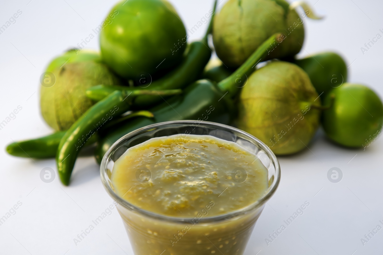 Photo of Bowl with delicious salsa sauce and ingredients on white background, closeup