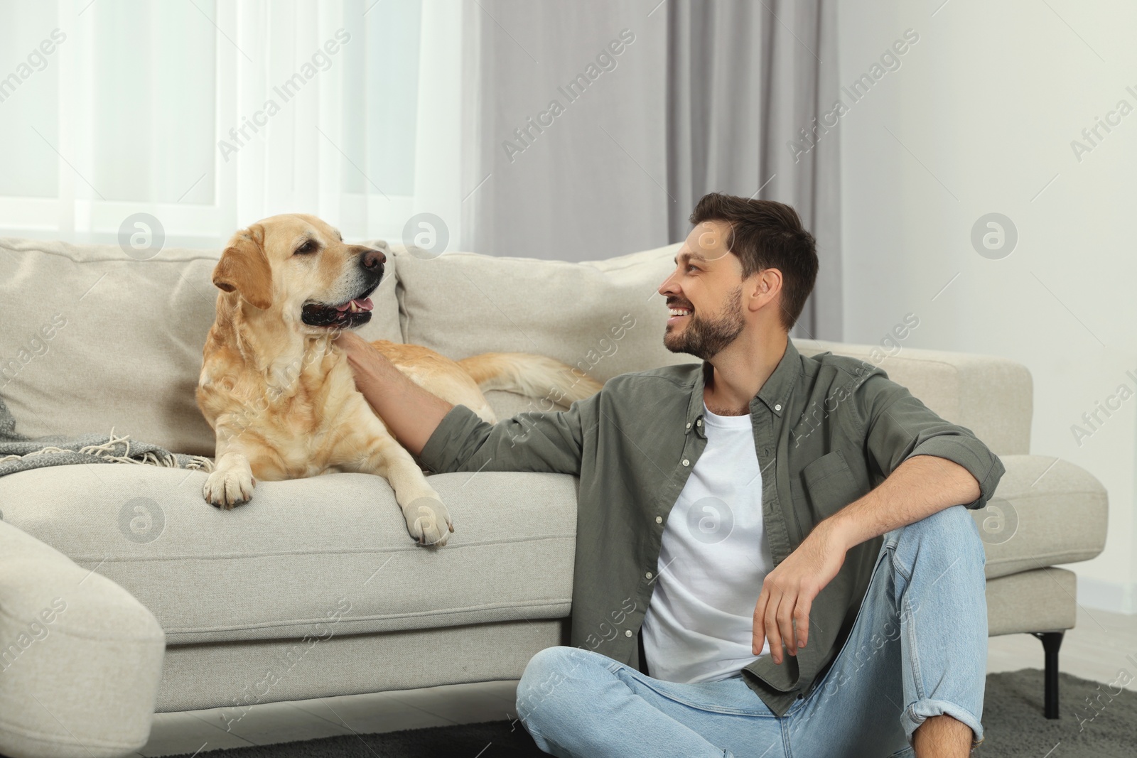 Photo of Happy man with his cute Labrador Retriever at home