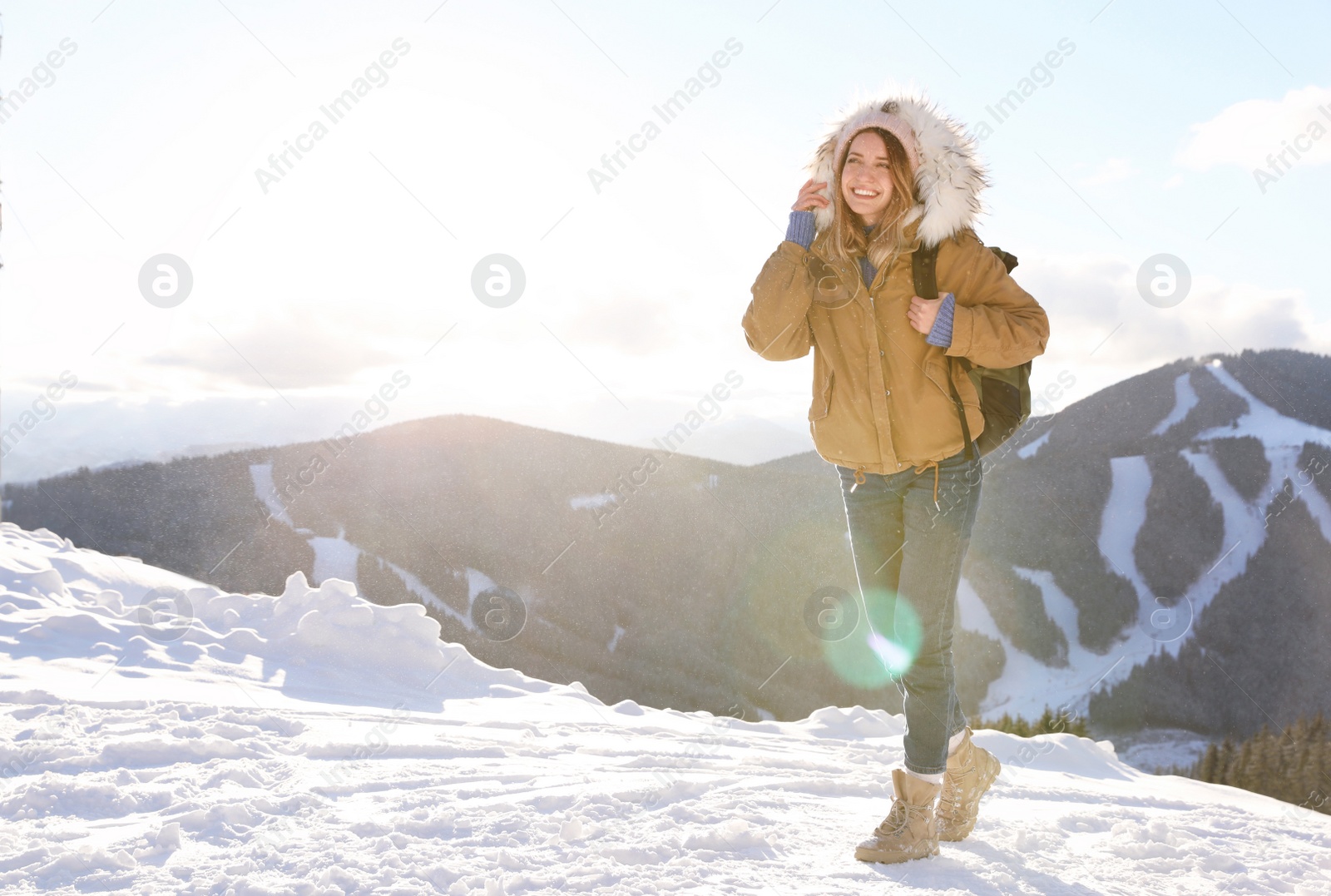 Photo of Happy young woman with backpack spending winter vacation in mountains. Space for text