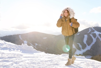 Photo of Happy young woman with backpack spending winter vacation in mountains. Space for text