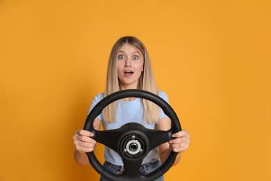 Photo of Emotional young woman with steering wheel on yellow background