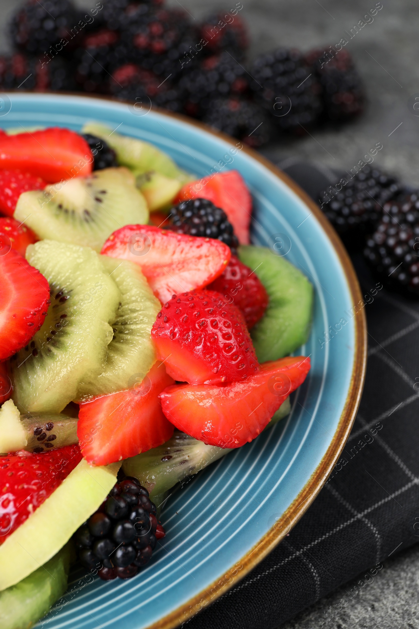 Photo of Plate of delicious fresh fruit salad on table, closeup