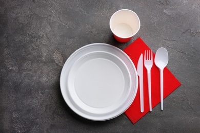 Composition with plastic dishware on grey background, flat lay. Picnic table setting