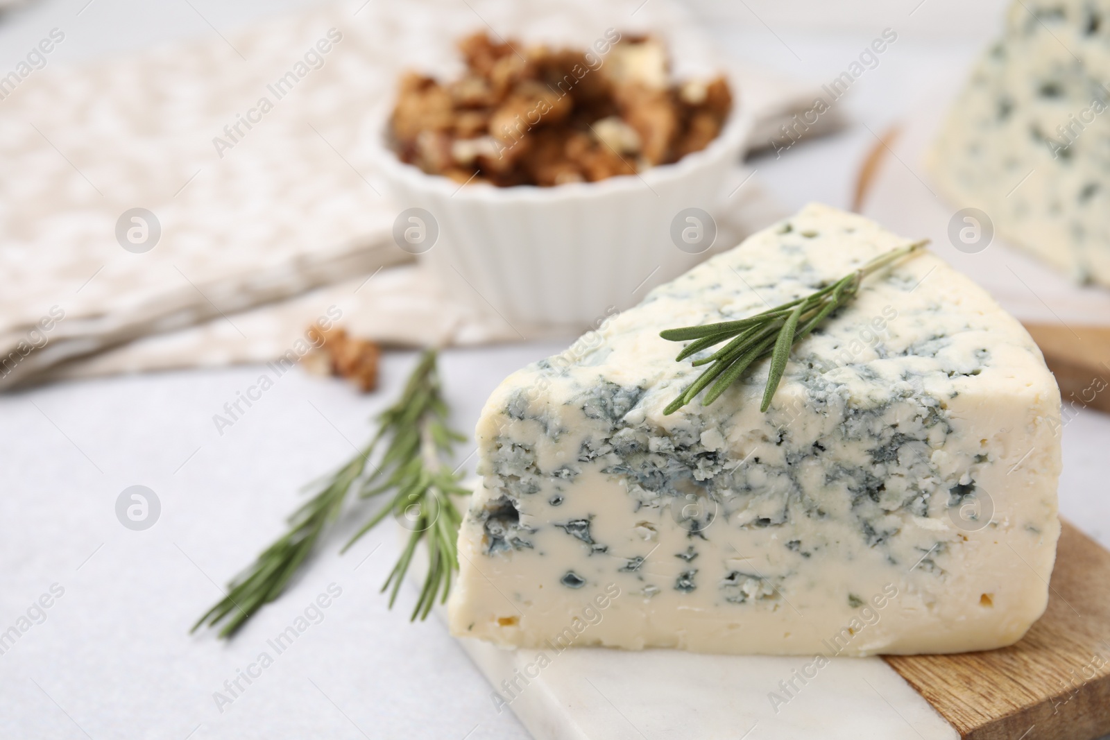 Photo of Tasty blue cheese with rosemary on light table, closeup. Space for text