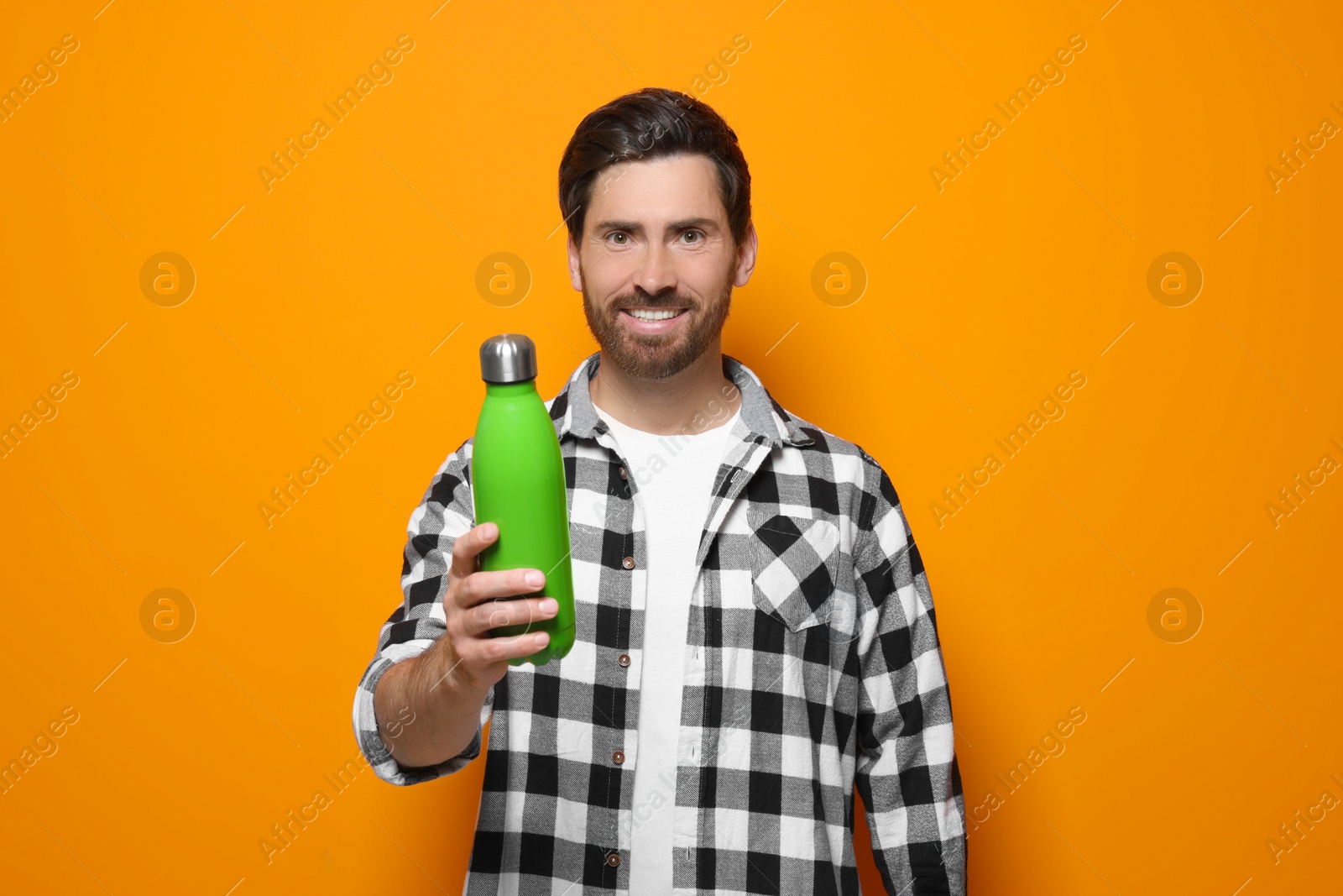 Photo of Man with green thermo bottle on orange background