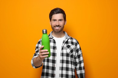 Man with green thermo bottle on orange background