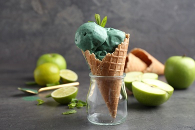 Photo of Composition with delicious spirulina ice cream cone on table against grey background