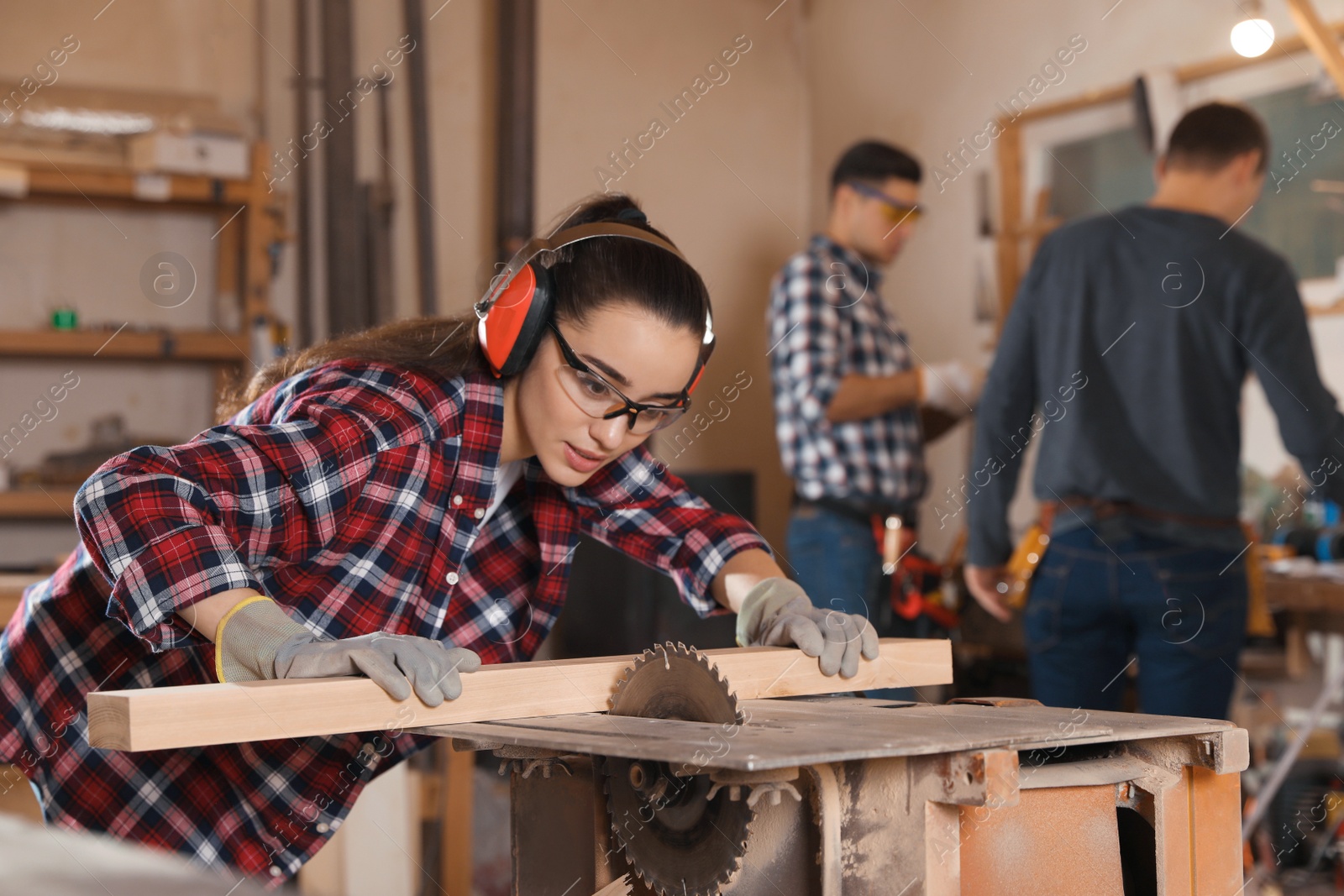 Photo of Professional carpenter working with sawmill machine near colleagues in workshop