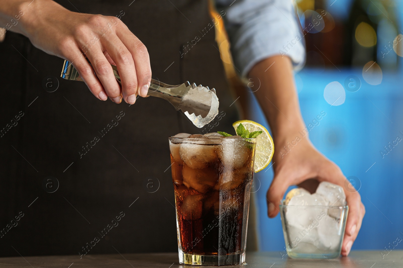 Photo of Woman preparing fresh alcoholic cocktail with lemon and mint at bar counter, closeup