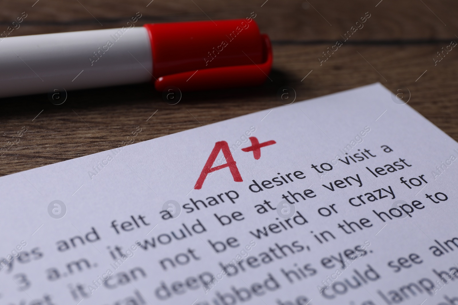 Photo of School grade. Sheet of paper with red letter A, plus symbol and marker on wooden table, closeup