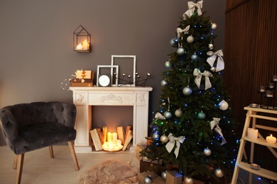 Photo of Stylish room interior with Christmas tree and decorative fireplace