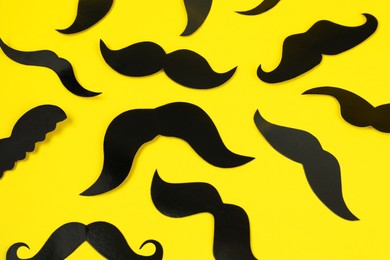 Many fake paper mustaches on yellow background
