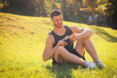 Photo of Happy man checking pulse with blood pressure monitor on finger after training in park. Space for text