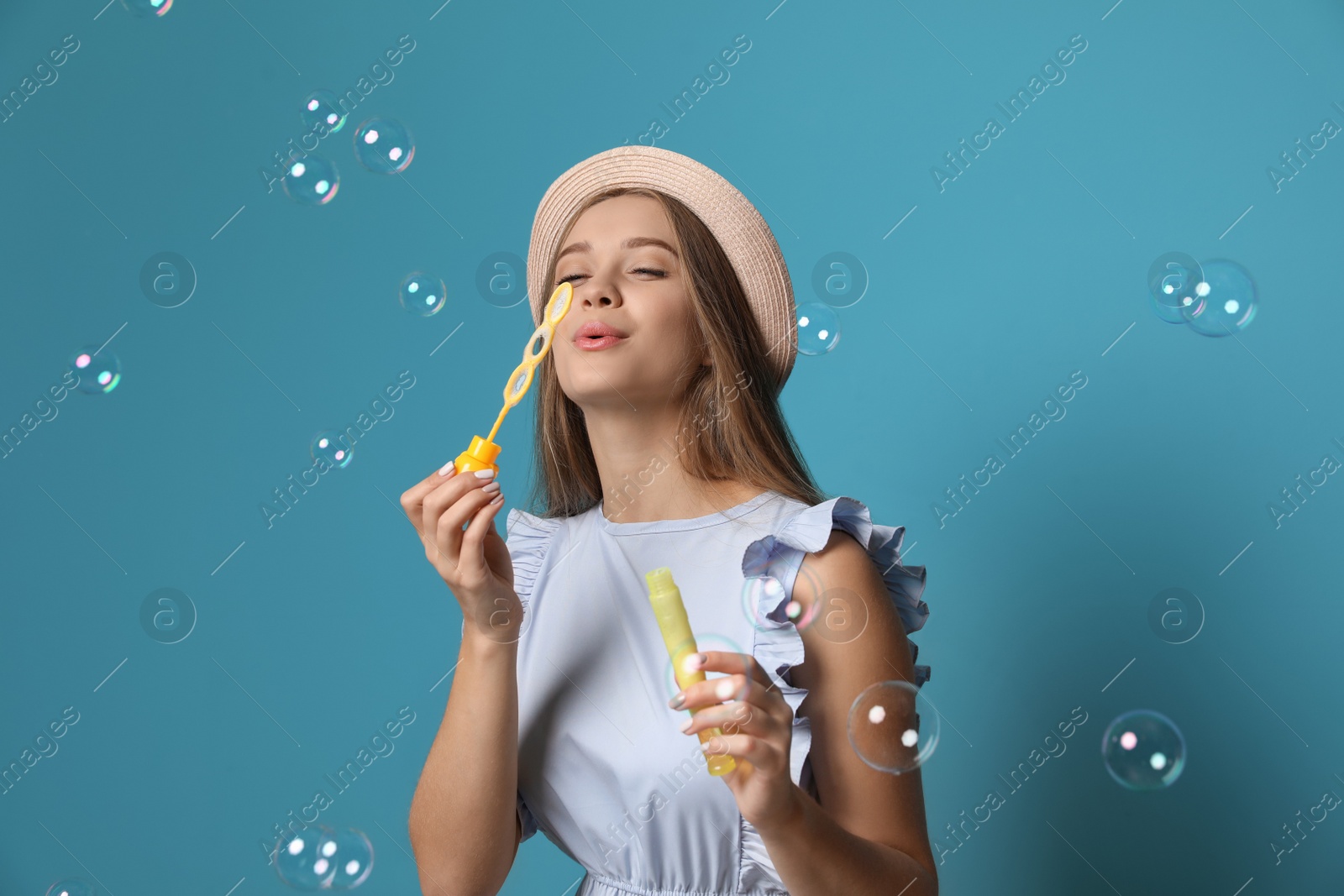 Photo of Young woman blowing soap bubbles on color background