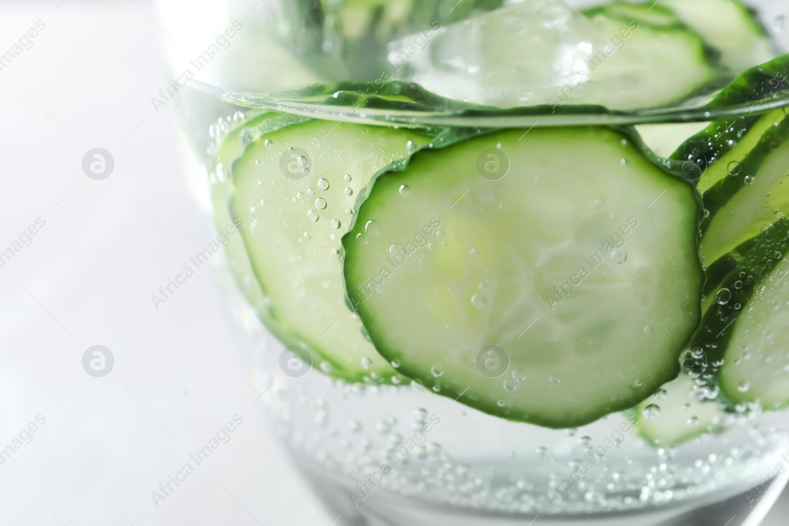 Photo of Glass of fresh cucumber water on light background, closeup