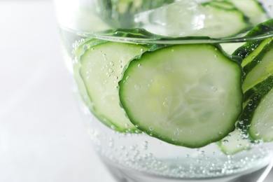 Photo of Glass of fresh cucumber water on light background, closeup