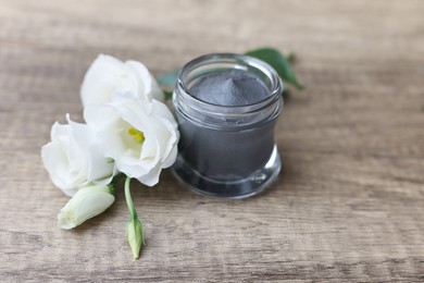 Jar of cosmetic mask and eustoma flowers on wooden table