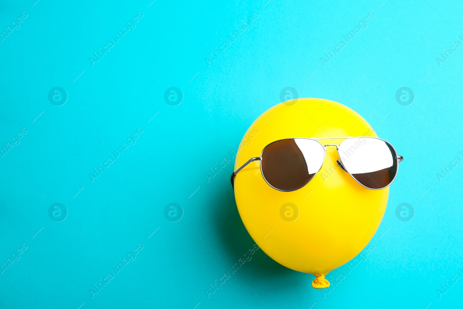 Photo of Balloon with sunglasses on blue background, top view. Space for text