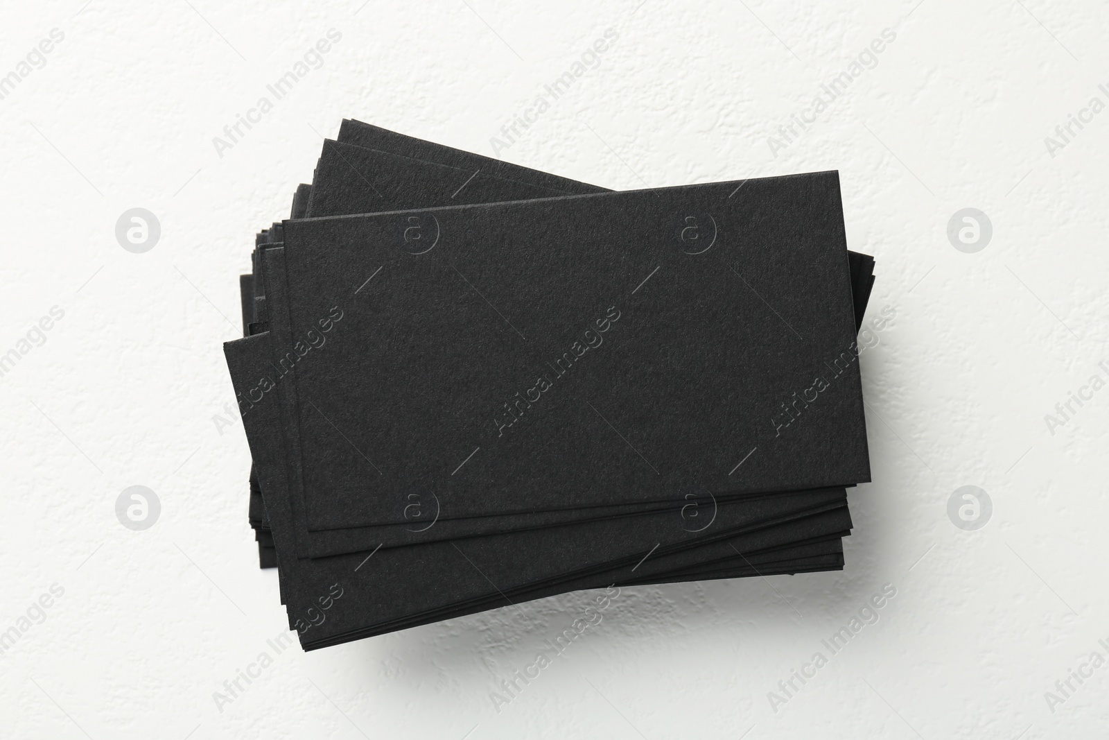 Photo of Blank black business cards on white table, top view