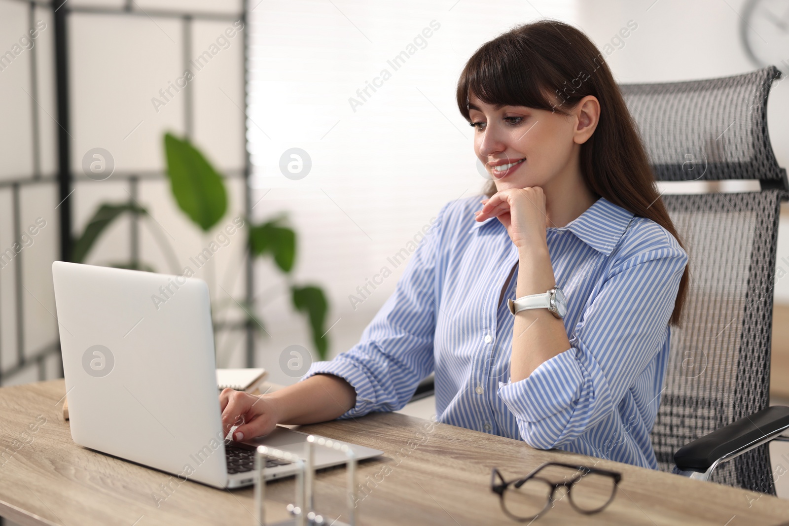 Photo of Woman watching webinar at wooden table in office