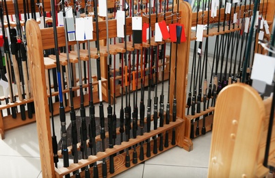 Photo of Stand with different fishing rods in sports shop