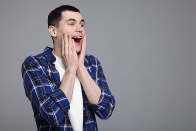 Portrait of surprised man on grey background, space for text