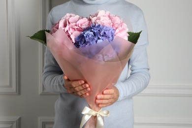 Photo of Woman with bouquet of beautiful hortensia flowers near white wall, closeup