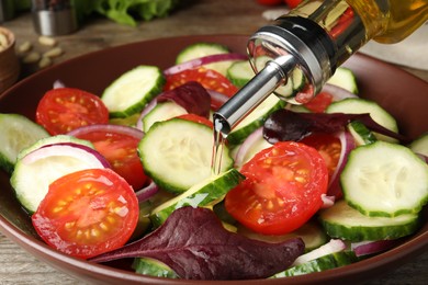 Photo of Adding cooking oil to delicious salad on table, closeup