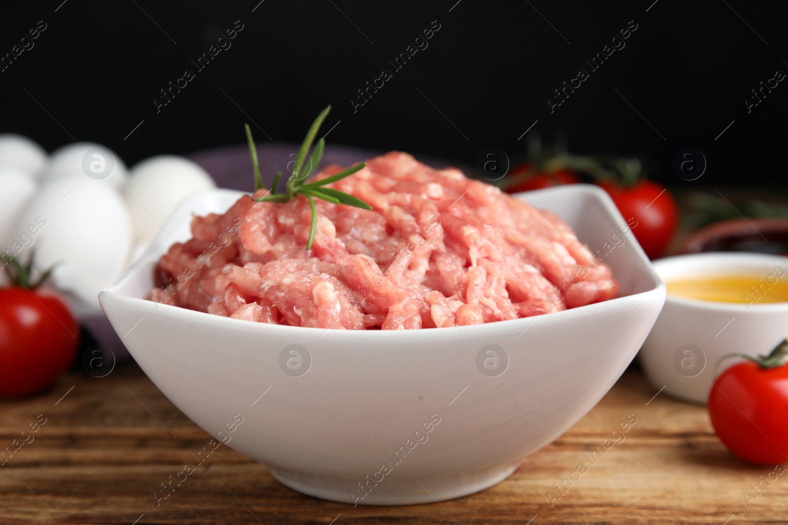 Photo of Raw chicken minced meat with rosemary on wooden table, closeup