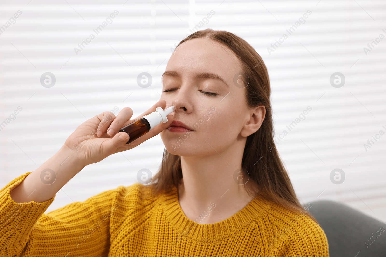 Photo of Medical drops. Young woman using nasal spray indoors