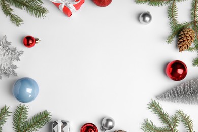 Photo of Christmas greeting card with space for text. Flat lay composition of fir tree branches and festive decor on white background