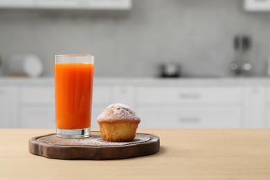 Photo of Delicious cupcake and glass of juice on wooden table in kitchen. Space for text