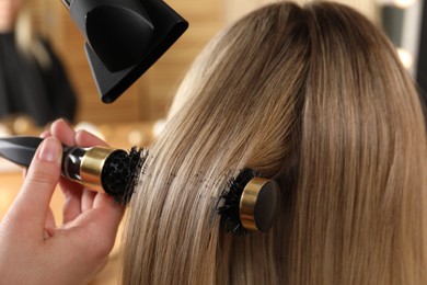 Photo of Hairdresser blow drying client's hair in salon, closeup