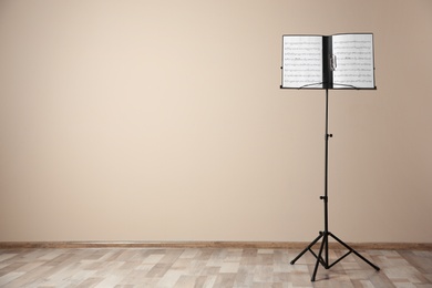 Note stand with music sheets near color wall indoors. Space for text