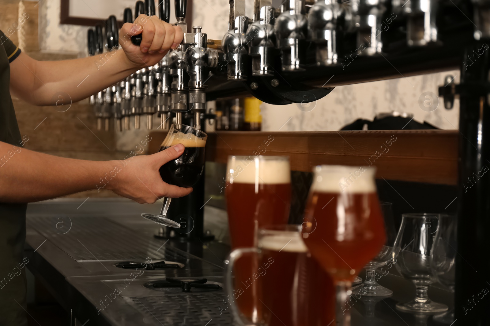 Photo of Bartender pouring fresh beer into glass in pub, closeup