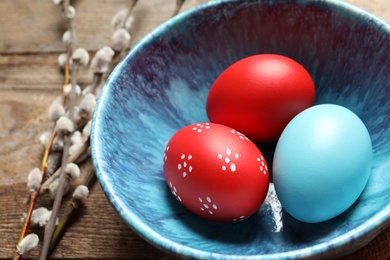 Photo of Bowl with painted Easter eggs on table, closeup