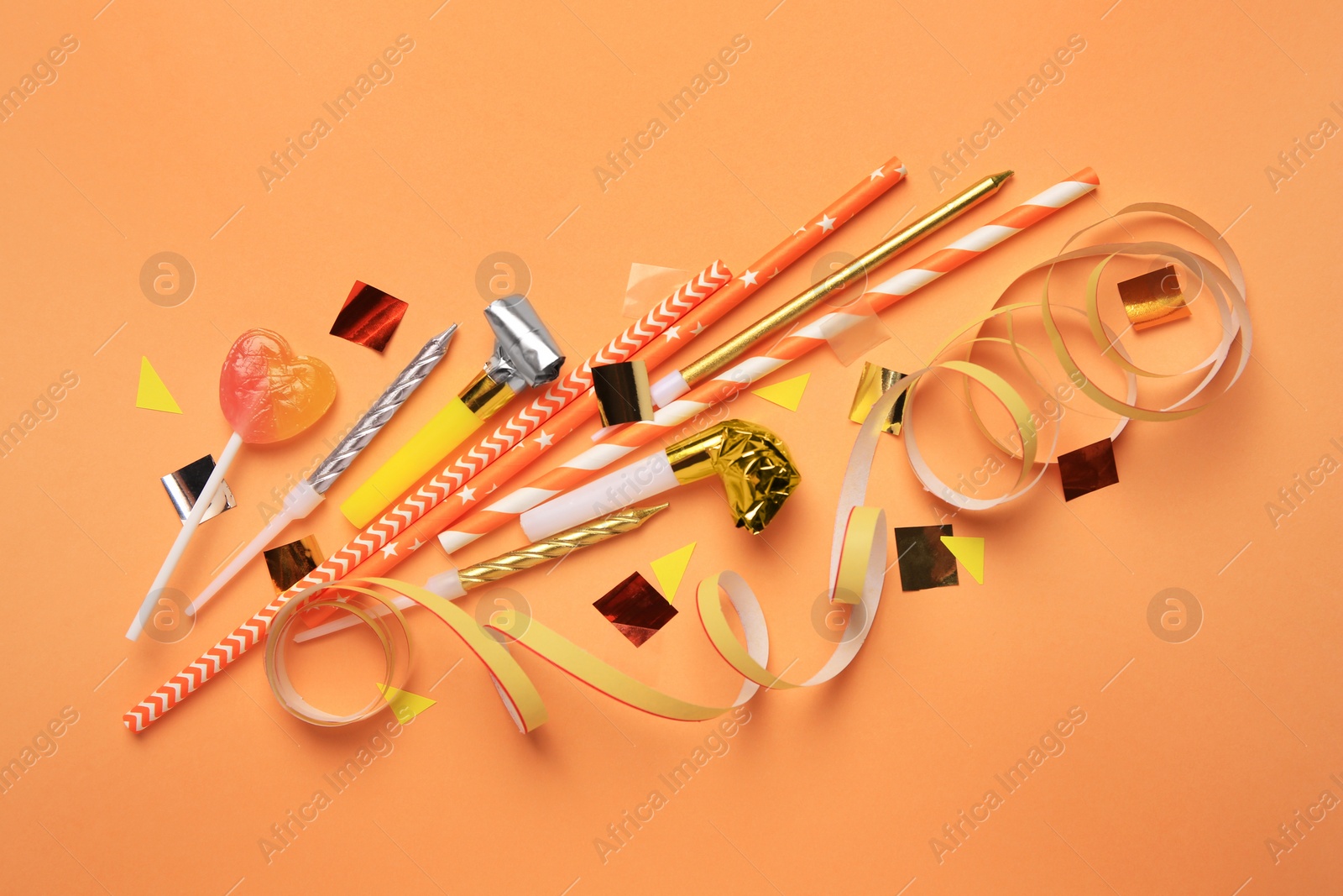 Photo of Party blowers, lollipop and festive decor on coral background, flat lay