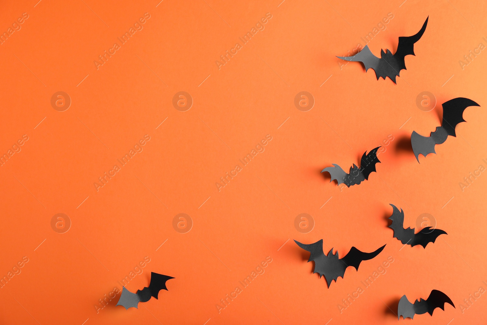 Photo of Paper bats on orange background, flat lay with space for text. Halloween decor