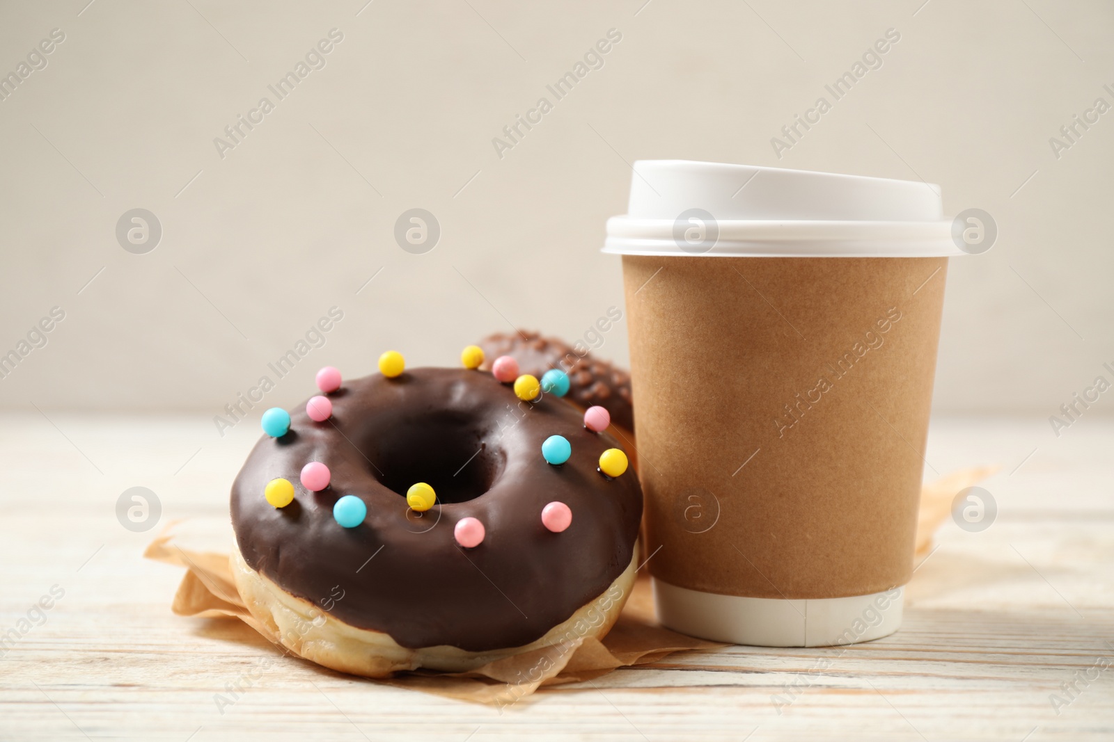 Photo of Delicious glazed donuts and coffee on white wooden table