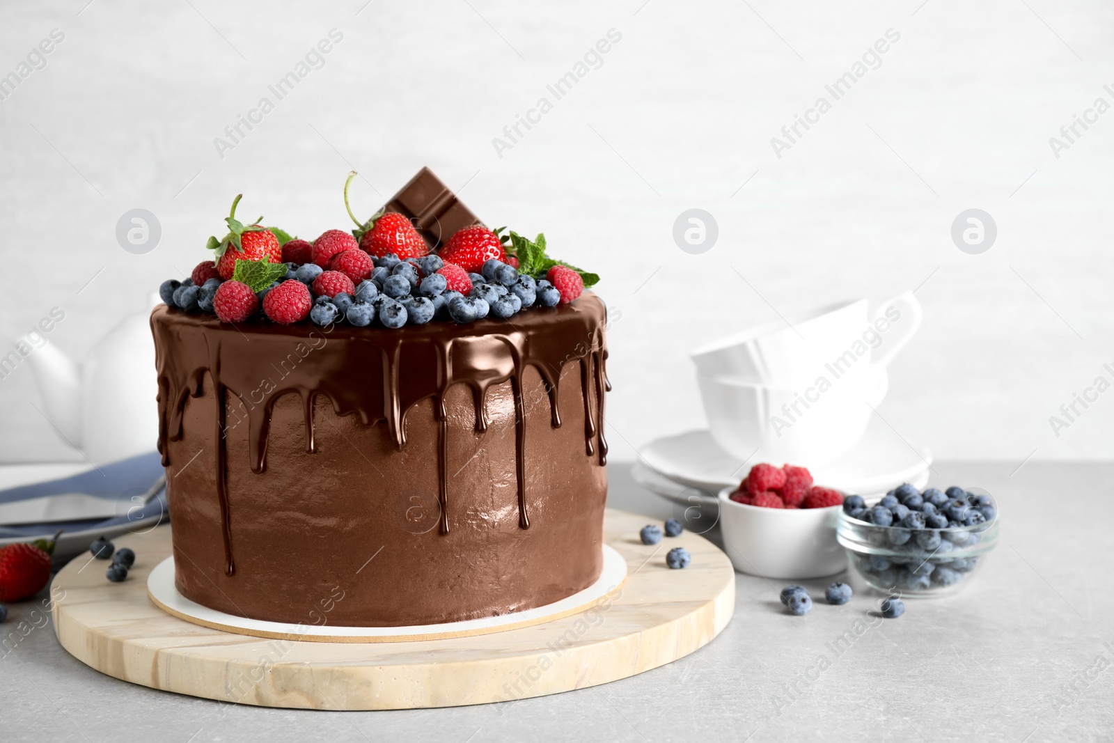 Photo of Freshly made delicious chocolate cake decorated with berries on white table