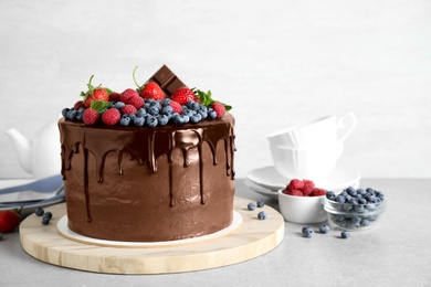 Photo of Freshly made delicious chocolate cake decorated with berries on white table