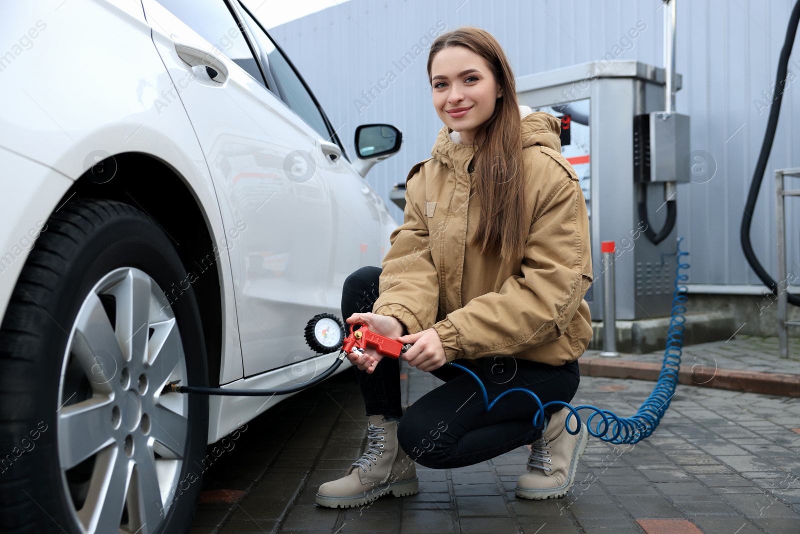 Photo of Young woman inflating tire at car service