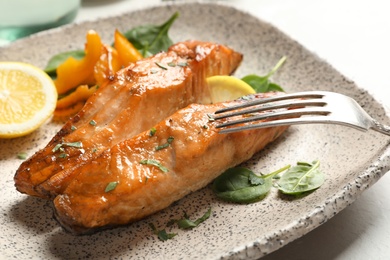 Photo of Tasty cooked salmon with lemon on plate, closeup