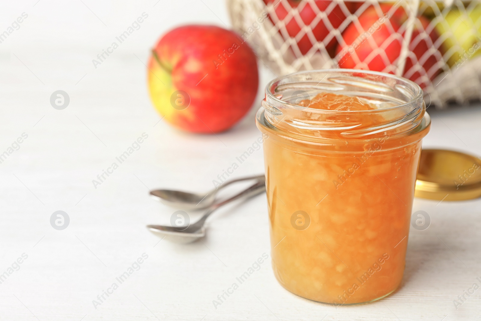 Photo of Homemade delicious apple jam on white wooden table. Space for text