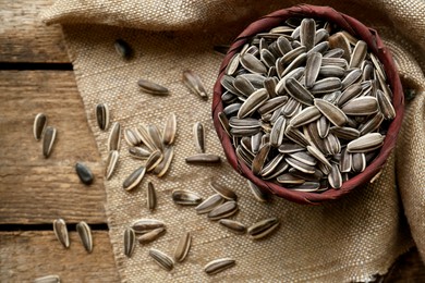 Photo of Organic sunflower seeds on wooden table, flat lay. Space for text