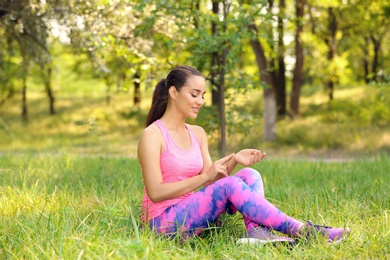 Photo of Young woman checking pulse outdoors on sunny day